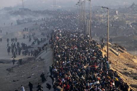 Internally displaced Palestinians walk on Al Rashid road in central Gaza as they return