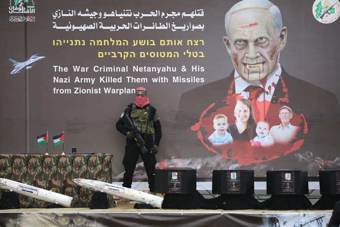 A Palestinian militant group Hamas fighter stands in front of a banner on stage