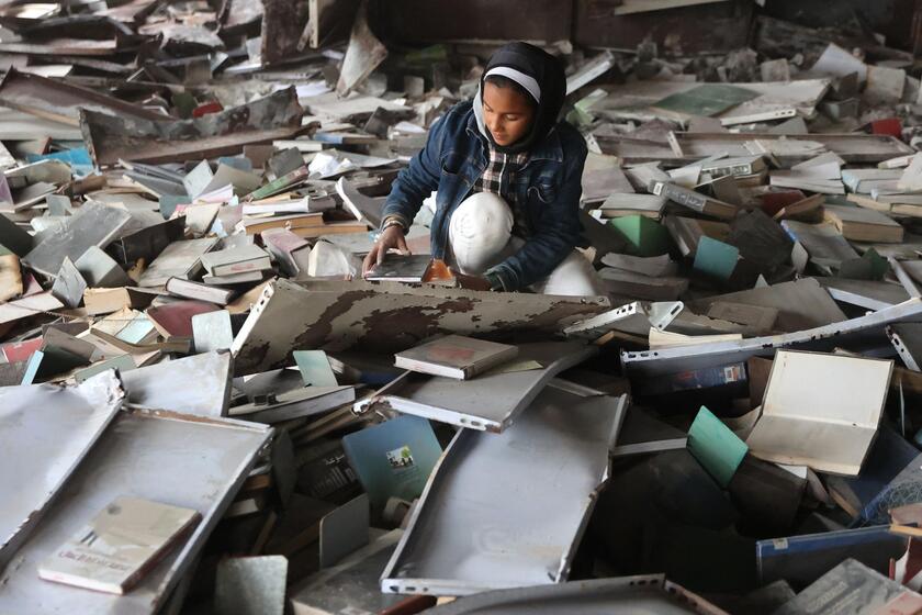 Palestinesi sfollati raccolgono libri dall'università distrutta per bruciarli e cucinare cibo