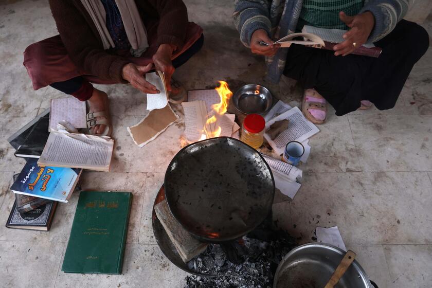 Palestinesi sfollati raccolgono libri dall'università distrutta per bruciarli e cucinare cibo