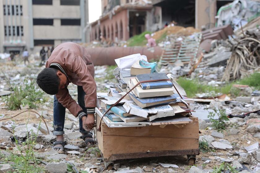 Palestinesi sfollati raccolgono libri dall'università distrutta per bruciarli e cucinare cibo