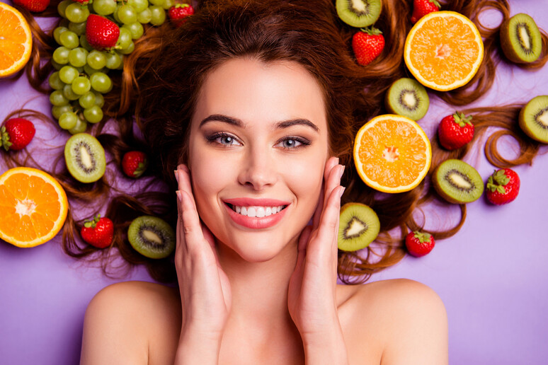 Una donna sorridente su un letto di frutta foto iStock. - RIPRODUZIONE RISERVATA